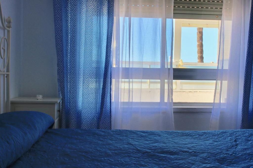 加的斯AranPe PLAYA CÁDIZ的一间卧室配有床和带窗帘的窗户