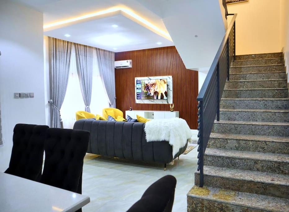 KarsanaLush Meadows Apartments的一间卧室配有一张床,楼梯配有沙发