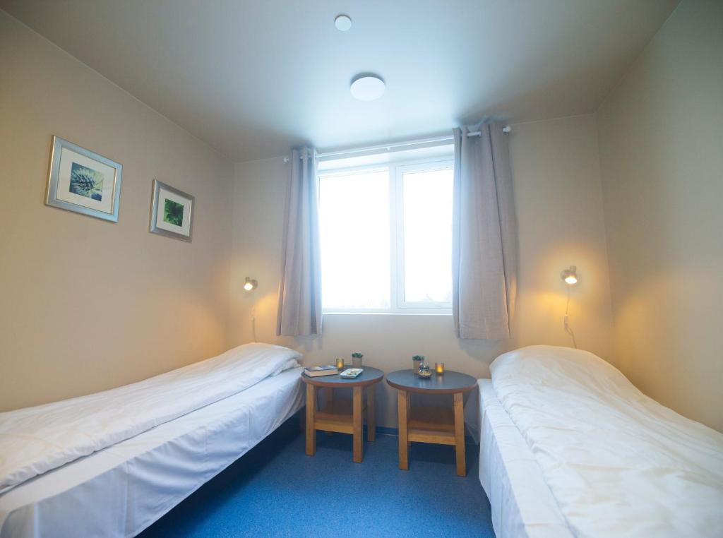 ØrskogSjøholt Sommerhotell的配有2张床的带窗户和2张桌子的客房