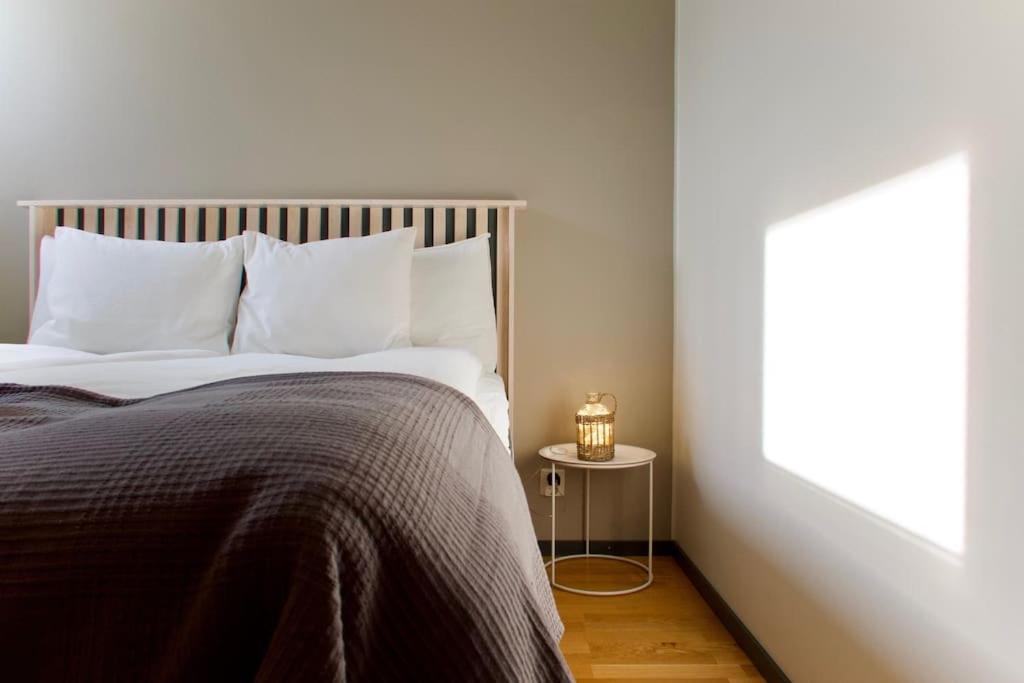 坦佩雷Raikas 2021 paritalo keskustassa, Sauna, P-paikka的卧室内的一张带白色枕头和灯的床