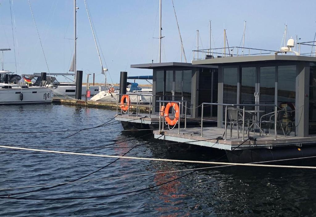 温德托尔夫Hausboot Fjord Aquila mit Dachterrasse in Wendtorf的两艘船停靠在水面上的码头