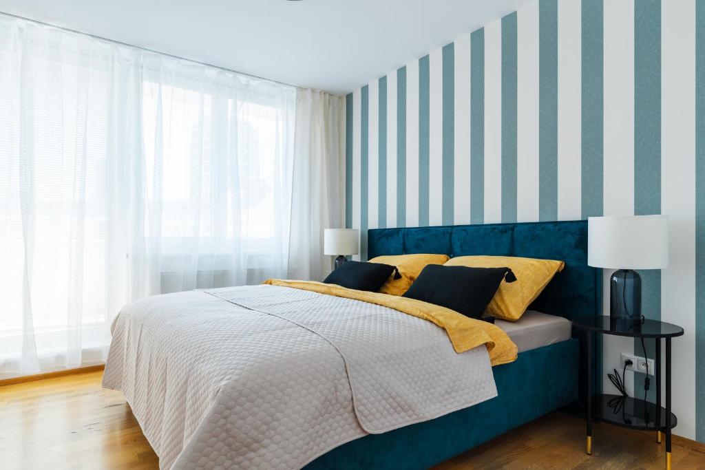 布拉迪斯拉发Business & Family Ambiente Apartments的一间卧室配有一张蓝色的床和条纹墙