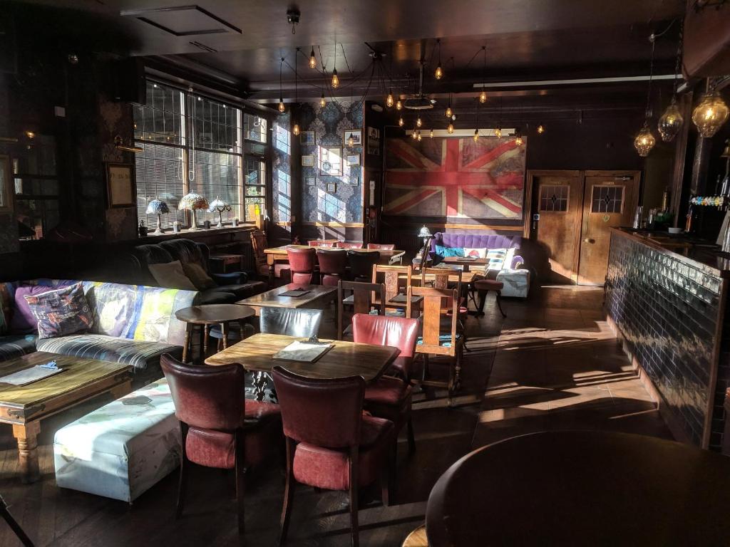伦敦华乐斯酒吧旅舍的餐厅设有桌椅和沙发。
