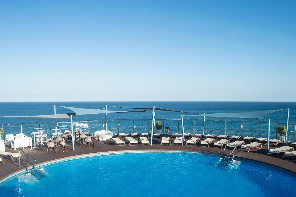 福恩吉罗拉爱尔波多皮埃尔假日酒店的一个带椅子的游泳池,背景是大海