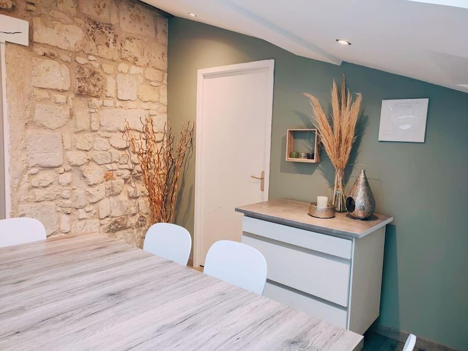 索米尔Maison chaleureuse située à Saumur的一间设有桌椅和石墙的用餐室