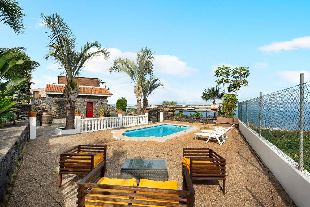洛斯雷亚莱霍斯Finca Viña Maria的后院设有游泳池、椅子和房屋