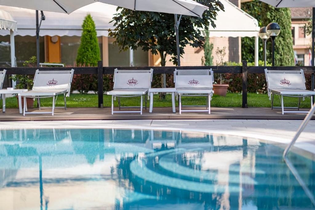 加尔达Hotel Imperial ***S的游泳池旁的两把椅子和一把遮阳伞