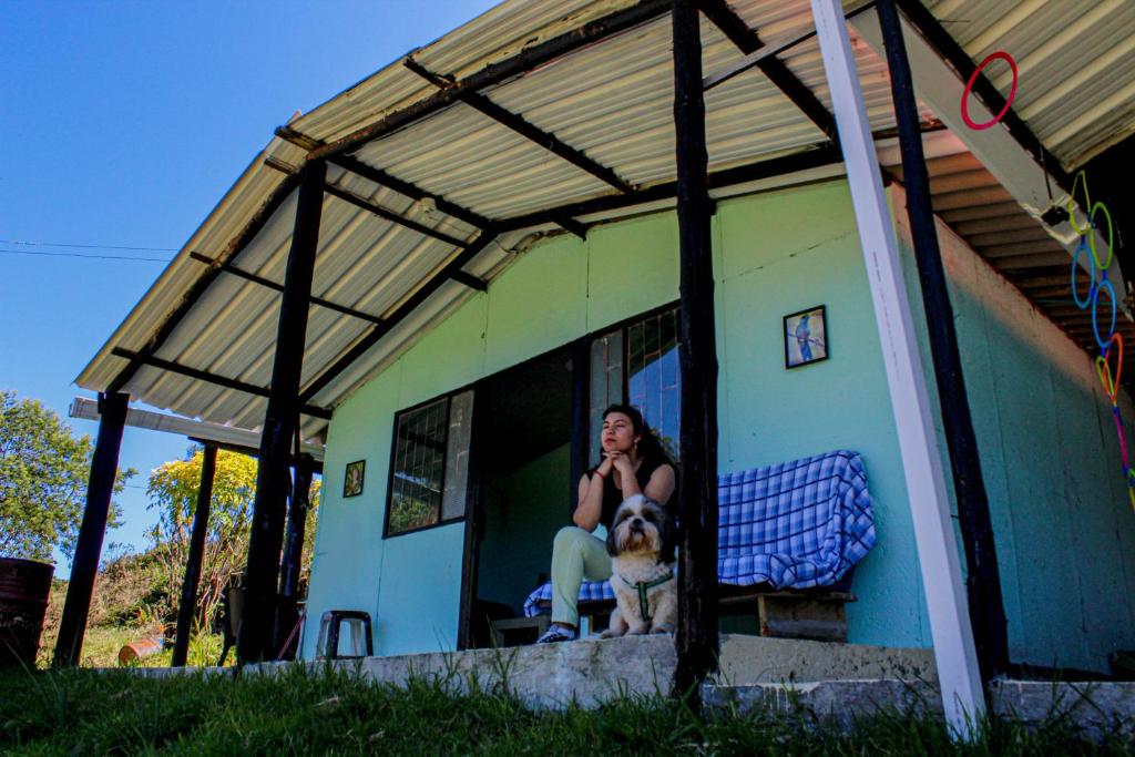 拉卡莱拉Acogedora cabaña entre las montañas de La Calera- Colombia的坐在房子窗户上的女人,带着狗