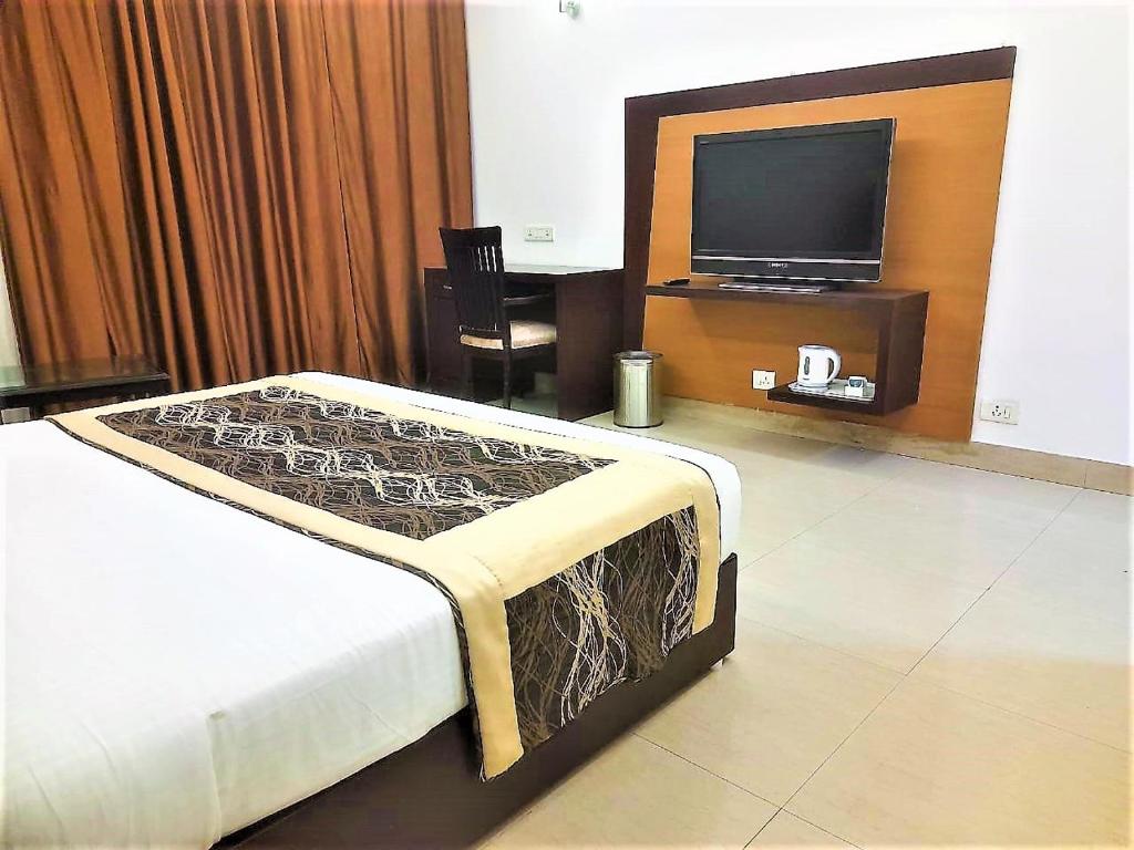 诺伊达Tavisha Villa Flim City Road Dadri Road的一间卧室配有一张床和一台平面电视