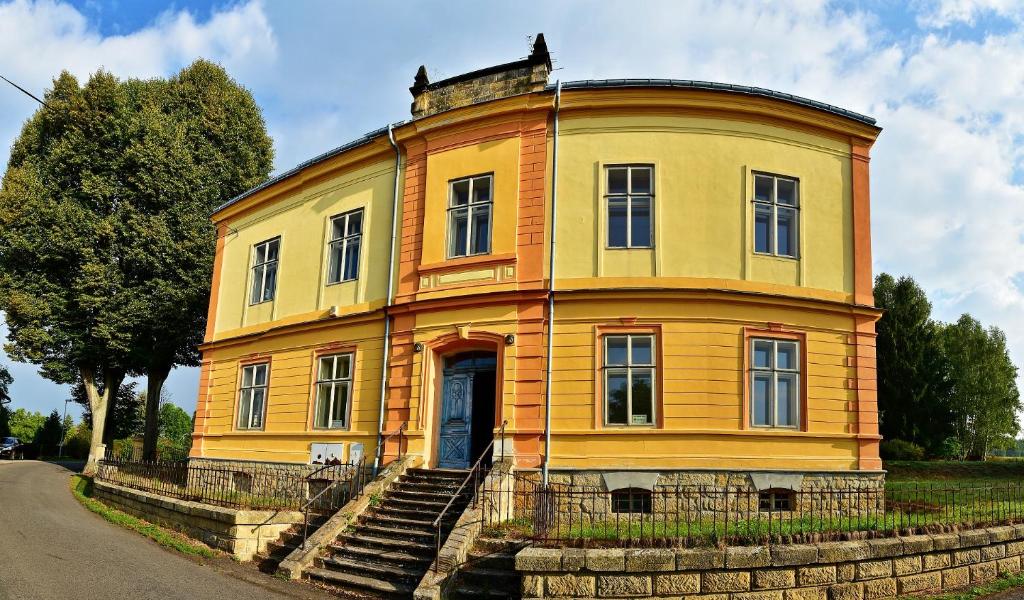 MeznáHotel Stará Škola的一座古老的黄色房子,前面有楼梯