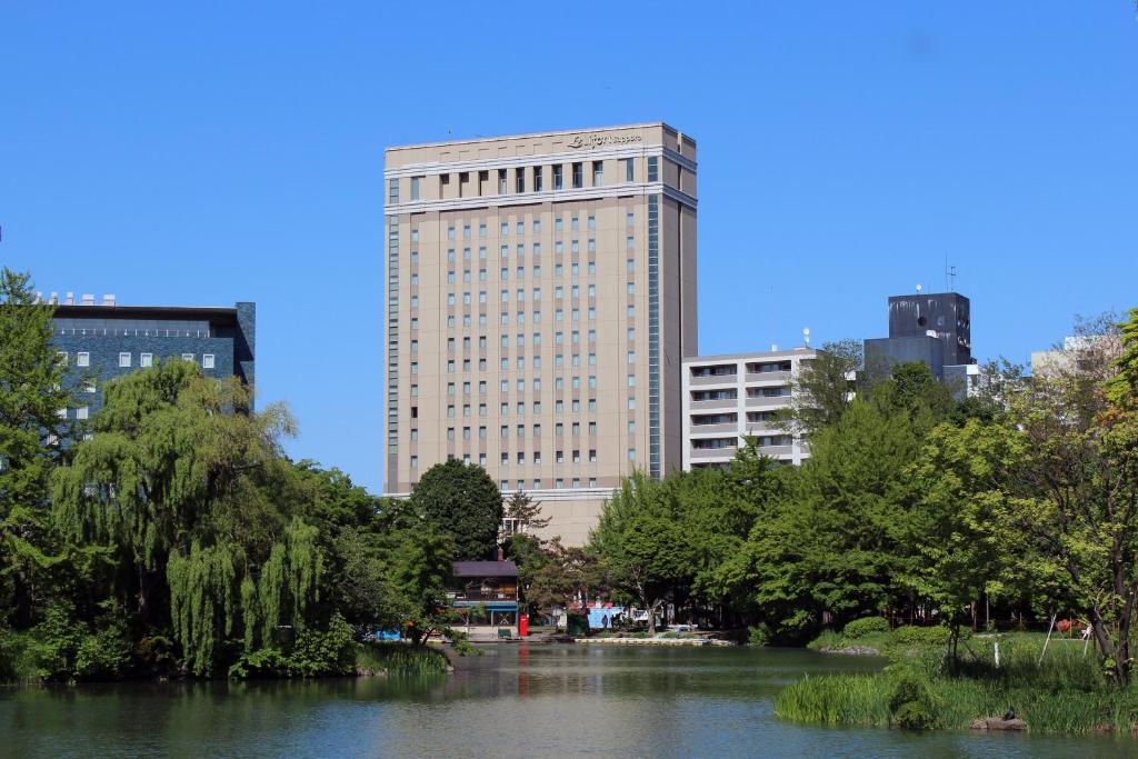 札幌莱福特札幌酒店的一座大建筑,在河前,有树木
