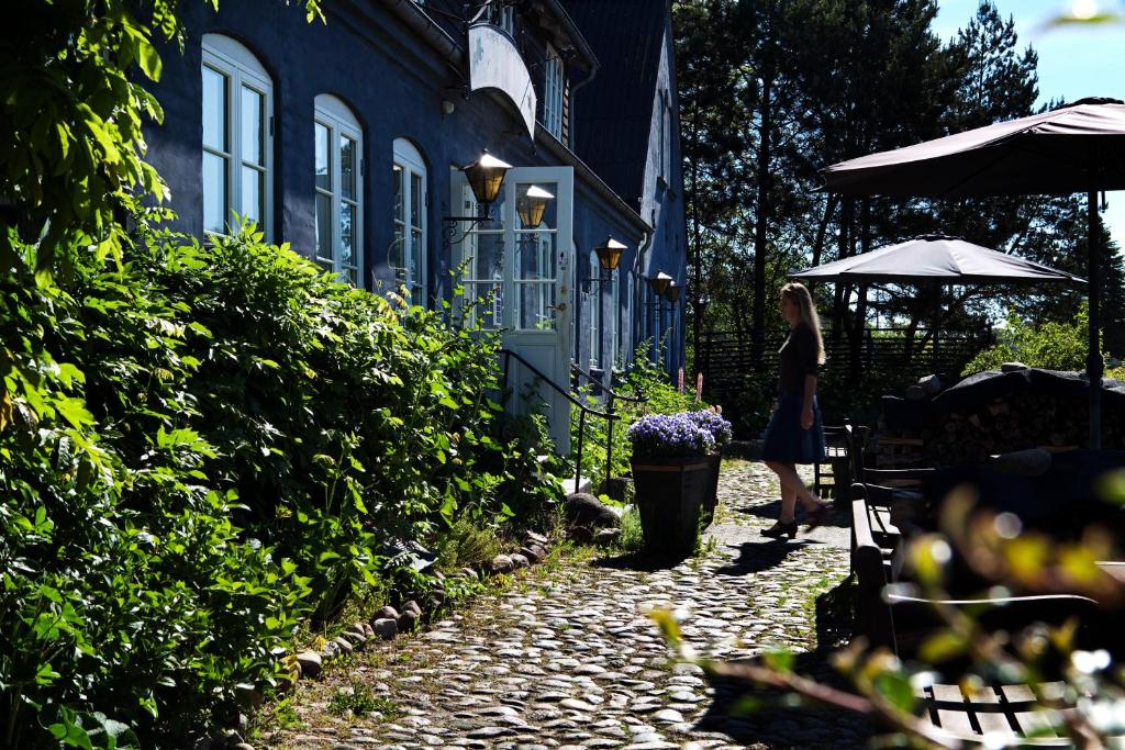 Nørre Vissing北辛库洛酒店的走在一块鹅卵石小道上,在房子前面的女人