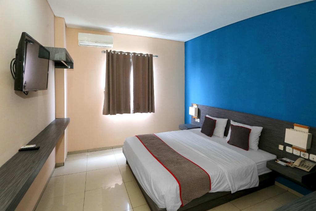 雅加达Super OYO Townhouse OAK Hotel Fiducia Pondok Gede的一间卧室设有一张大床和蓝色的墙壁