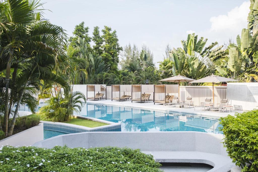奈扬海滩Dewa Phuket Resort & Villas的一个带躺椅和遮阳伞的游泳池