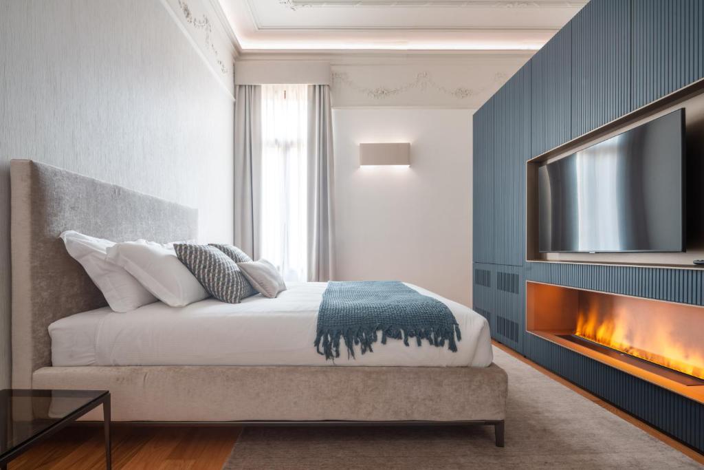 威尼斯Ninfea Luxury Suites的一间卧室设有一张带壁炉和电视的床。