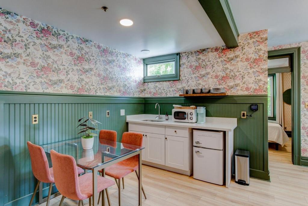 史普林维尔Suite 2 Historic Art City Inn的厨房配有玻璃桌和橙色椅子