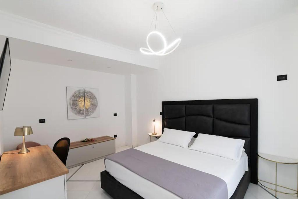 那不勒斯Apartments Hotel Real Suite Napoli Chiaia Mergellina的卧室配有1张床、1张桌子和1把椅子