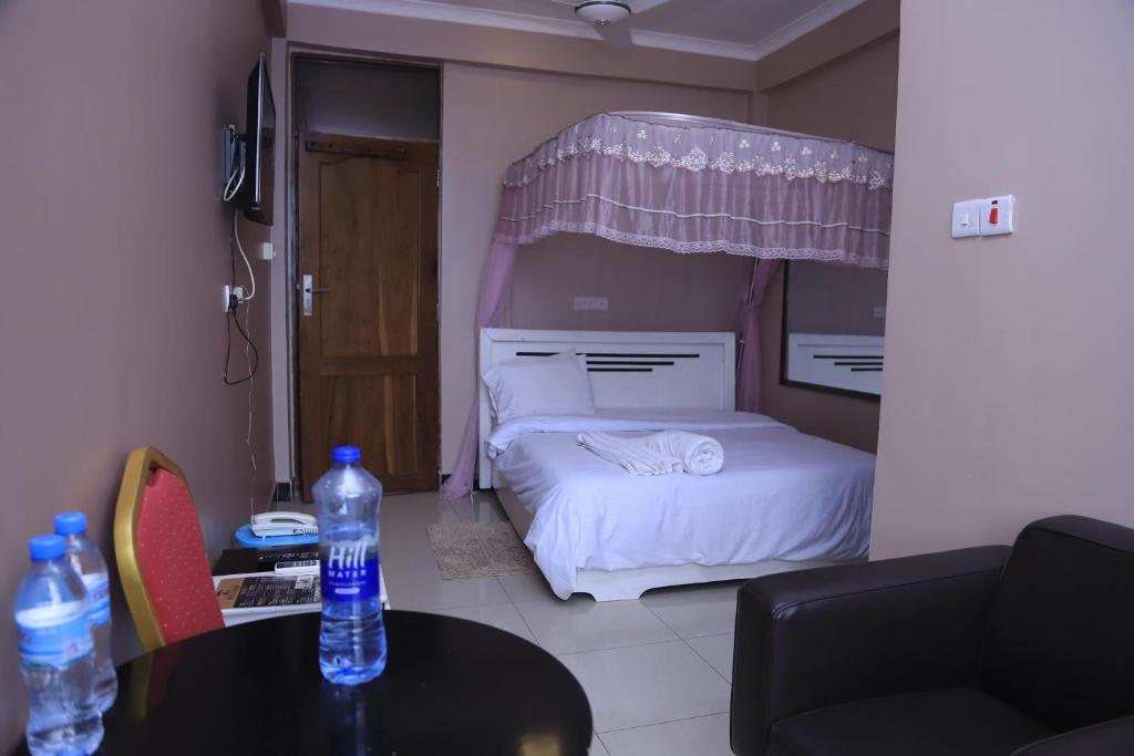 达累斯萨拉姆B10 Airport Lodge的一间卧室配有一张床和一张桌子,并提供2瓶水