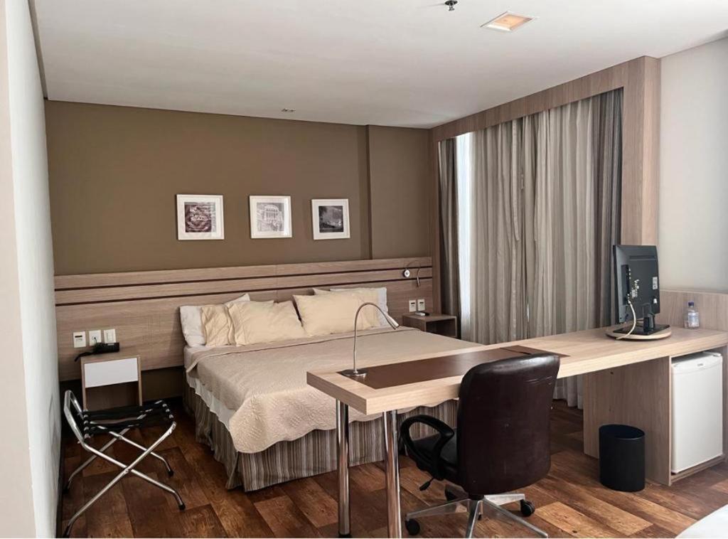 马瑙斯APART HOTEL SENSE II - Localizado em Hotel的一间卧室配有一张床和一张带电脑的书桌