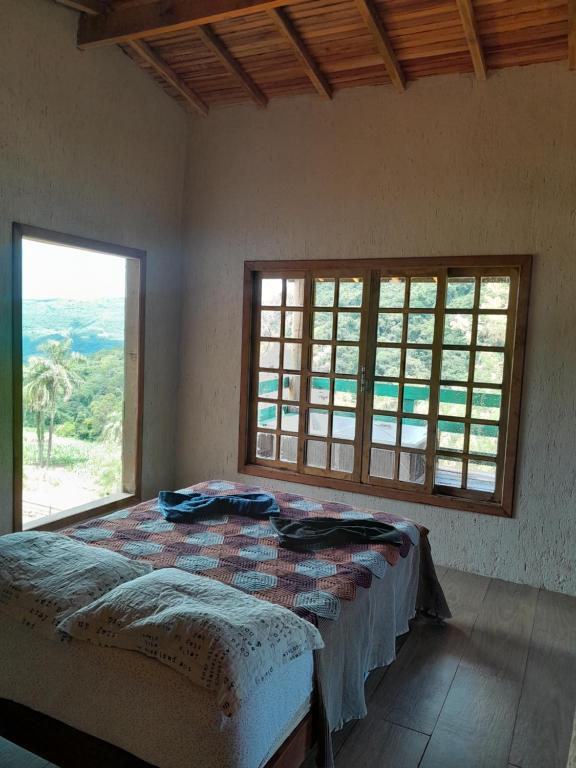 新彼得罗波利斯Chácara paraíso dá paz的一间卧室设有一张床和一个大窗户