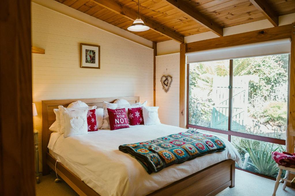 FranklinFleurty's Point Cottage at Franklin South, Huon Valley, Tasmania的一间卧室配有一张带红色枕头的大床