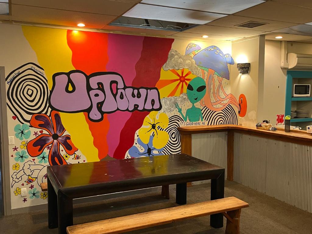 但尼丁UpTown Backpackers的一间设有桌子和多彩墙壁的房间