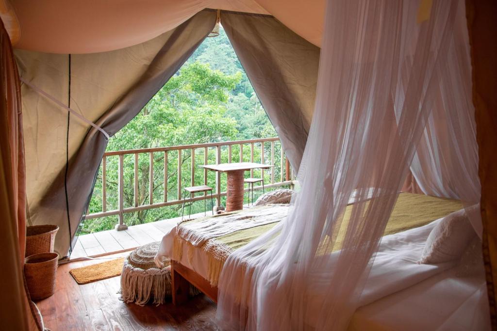 PatjungGlamping tent in Pelaga Eco Park的客房设有天蓬床和阳台。