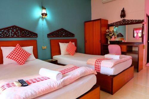 甘烹碧โรงแรม พี รีสอร์ท的一间卧室配有两张带红白色枕头的床