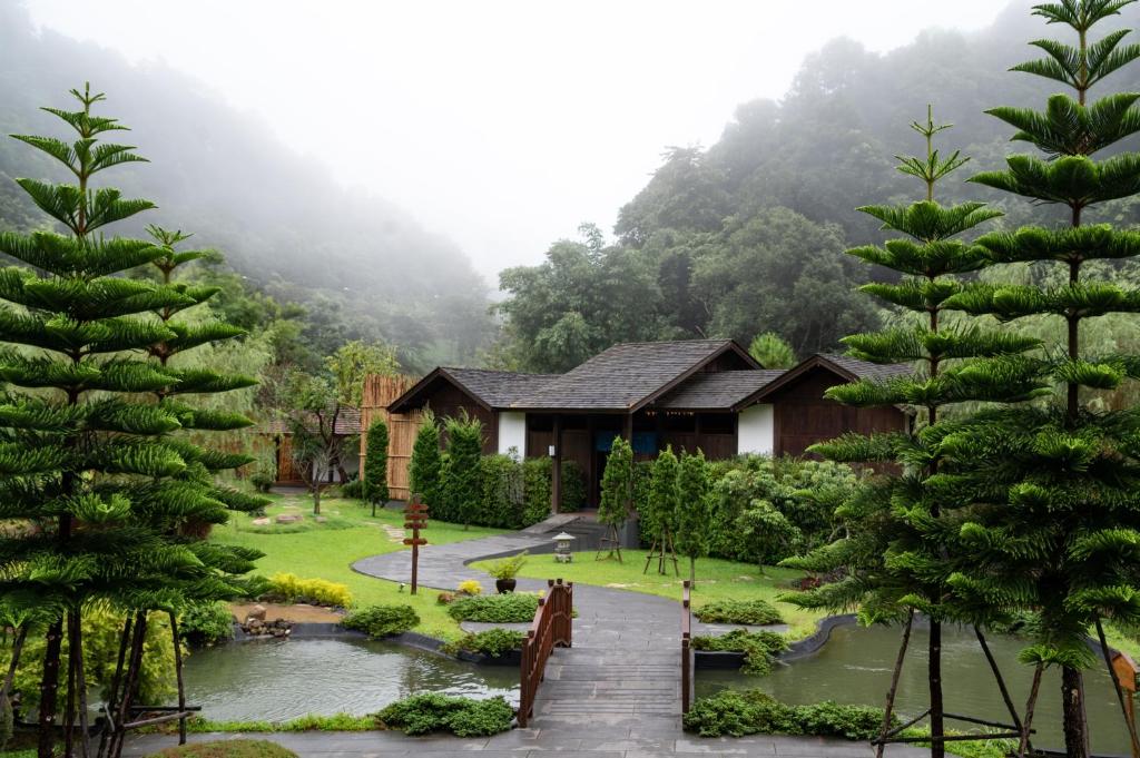 湄林蒙查温泉旅馆的一座带花园的房屋,前面有树木