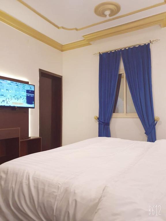 艾卜哈Basma Plaza的卧室配有白色床和蓝色窗帘