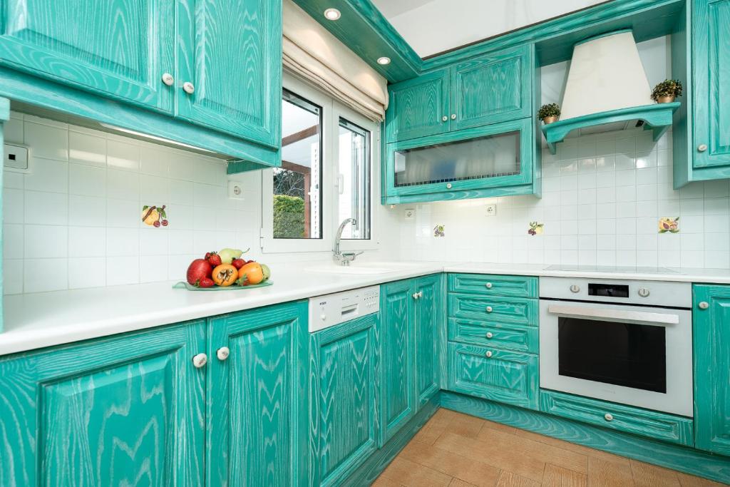 拉夫蒂港Coral Cottage House by A&D Properties的厨房配有蓝色橱柜和一碗水果