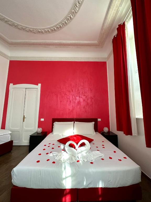罗马首都神殿旅馆的红色的卧室设有一张白色的床铺和红色的墙壁