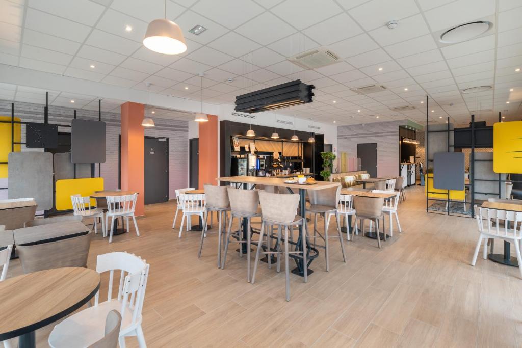 维里埃特B&B HOTELS Bourg-en-Bresse Viriat的一间设有白色桌椅的餐厅和一间酒吧