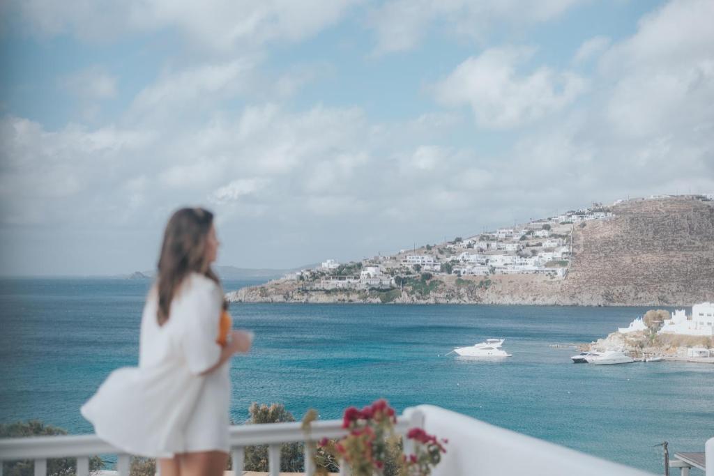 普拉迪斯亚罗斯myMykonos villa II的穿着白色衣服的女人,看着大海