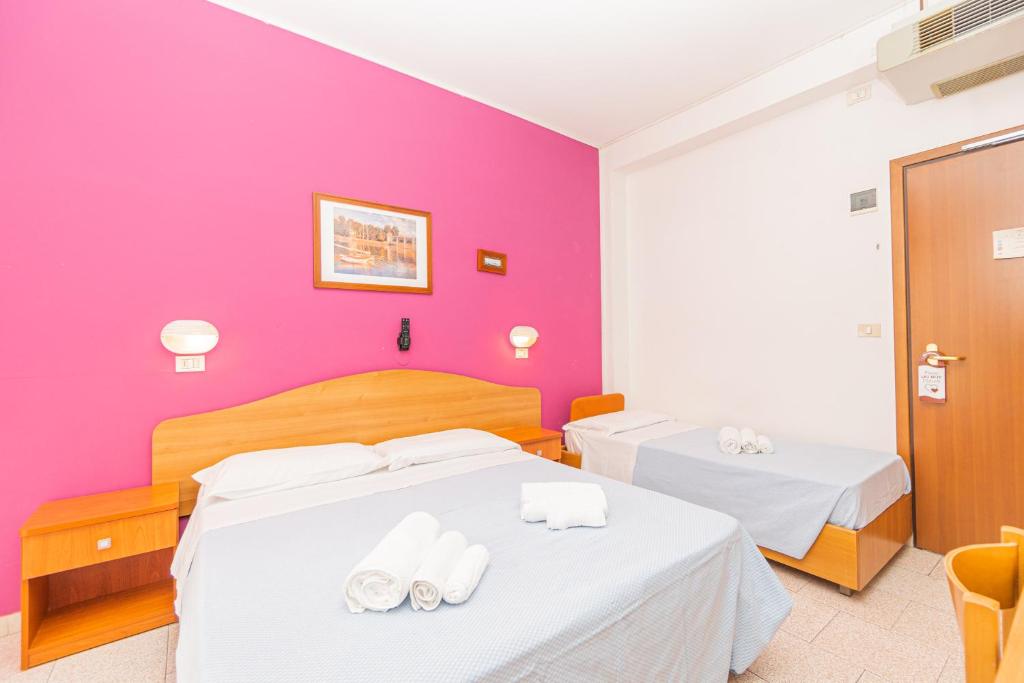 里米尼Hotel Arlino的配有两张床的带粉红色墙壁的客房