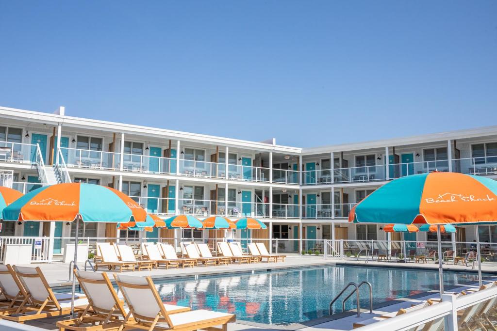 五月岬郡海滩小屋酒店的酒店游泳池设有椅子和遮阳伞