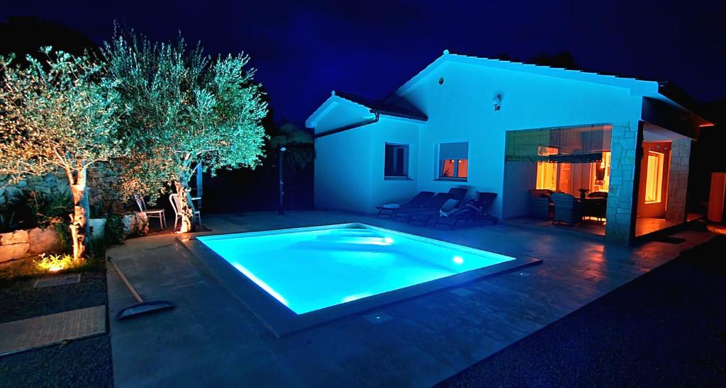 奥米沙利Villa Nevera的夜间在房子的院子中的一个游泳池