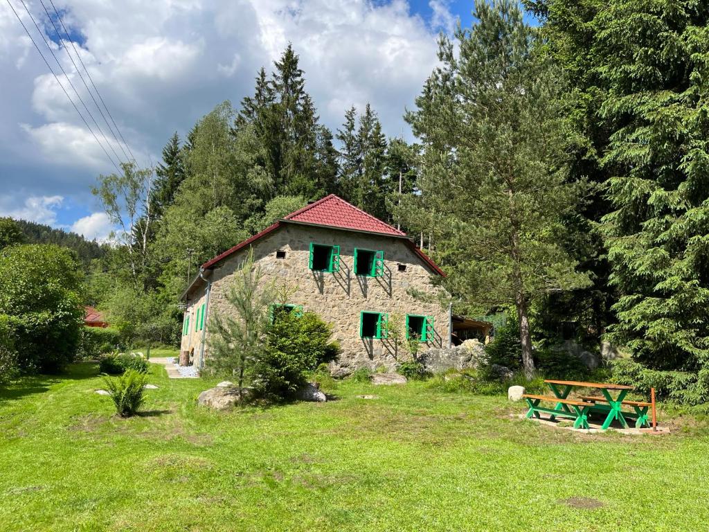 LoučoviceChalupa pod lipenskou hrází的一座带绿色百叶窗的石屋