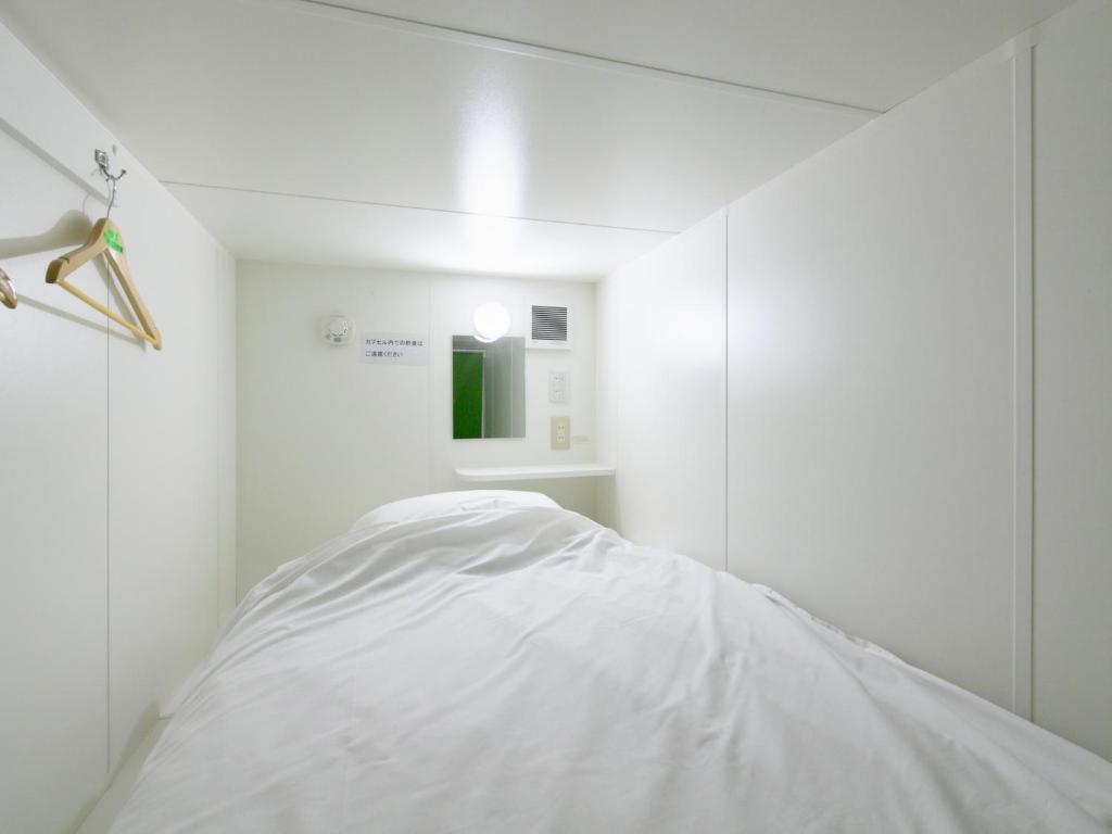 MidoriTabist カプセルイン笠懸 男性専用 Tabist Capsule Inn Kasakake Male Only的白色的客房配有床和镜子