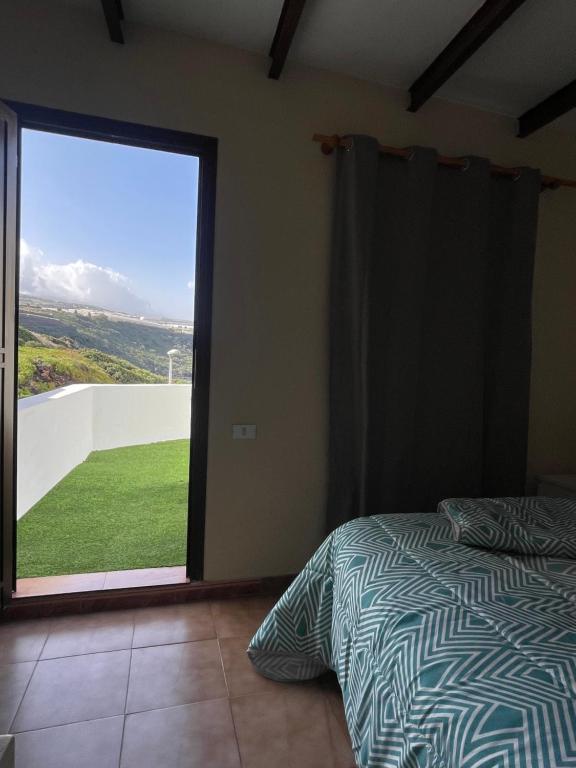 拉拉古纳Sunset Dream, casa en la playa con terraza的一间卧室设有一张床和一个大型滑动玻璃门