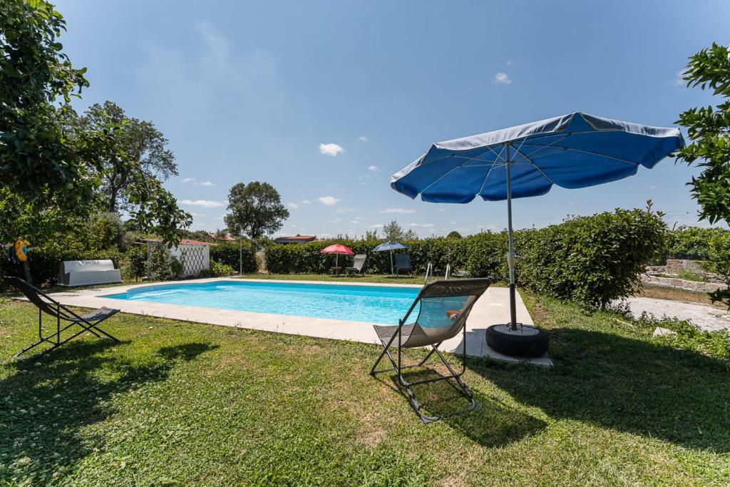 曼瓜尔迪Contemporary countryside haven in Mangualde的游泳池旁的蓝色遮阳伞和椅子