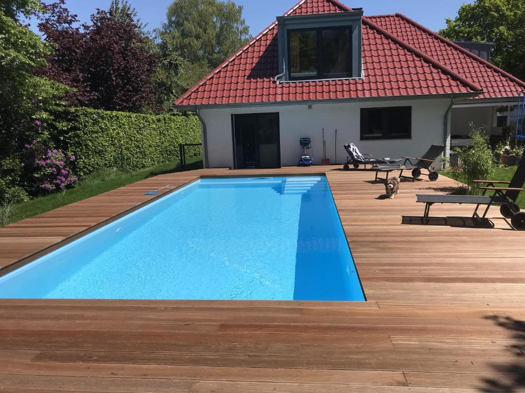 SchiffdorfHaus Kuestenperle的一个带木甲板和房子的游泳池