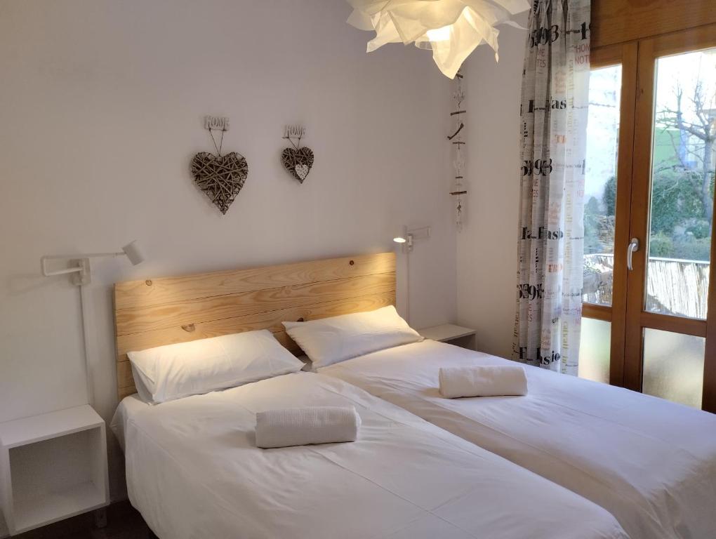 格劳斯Casas Natura的一间卧室设有两张带白色床单的床和窗户。