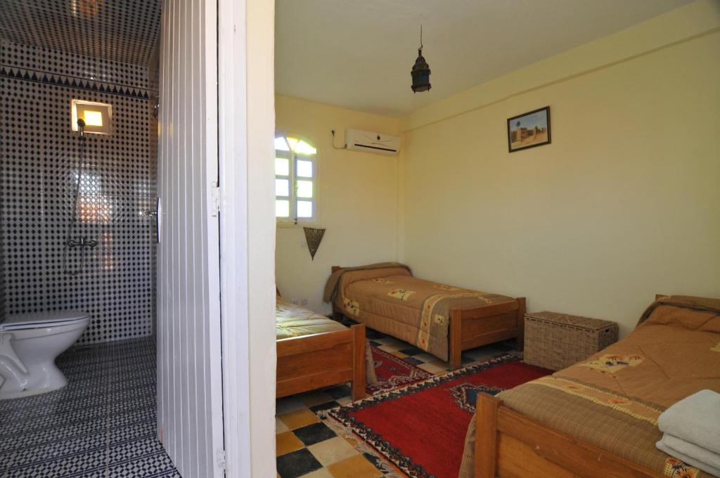 Sidi Abd el KaderRiad Freija-TAROUDANT的一间卧室设有两张床、一个浴缸和淋浴