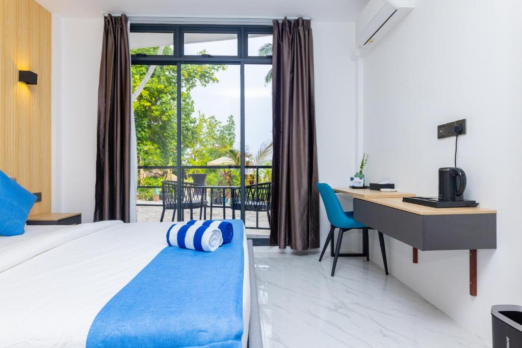 丹格迪Atoll Residence Dhangethi的配有一张床、一张书桌和一扇窗户的酒店客房