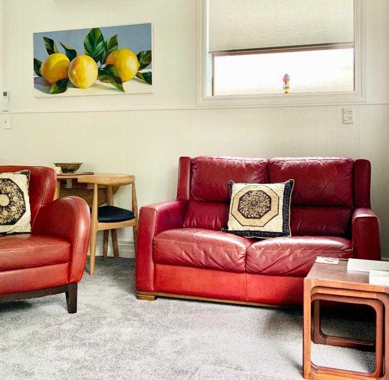 奥克兰The Partchery Devonport的客厅里设有一张红色的沙发和一把椅子