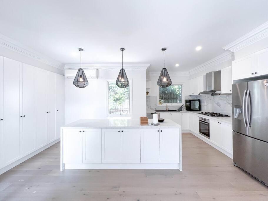 Mont AlbertLuxury Designer Home Villa Surrey Hills的白色的厨房配有白色橱柜和冰箱。