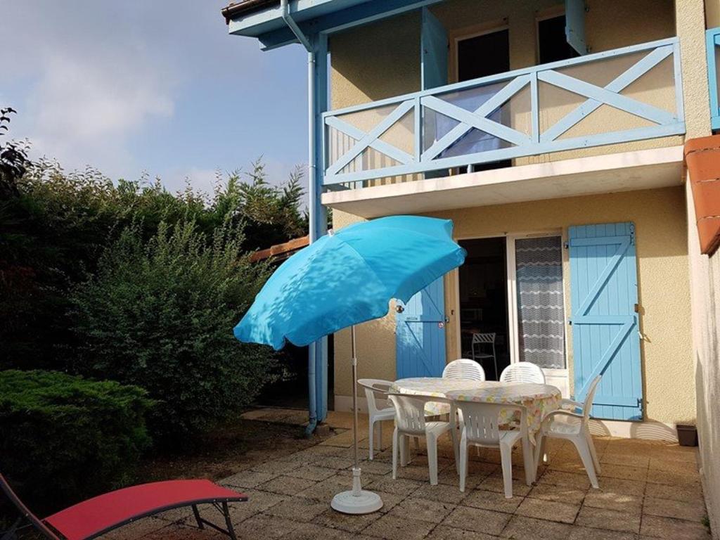 卡布勒通Maison Capbreton, 3 pièces, 4 personnes - FR-1-413-126的房子前的一张带蓝伞的桌子