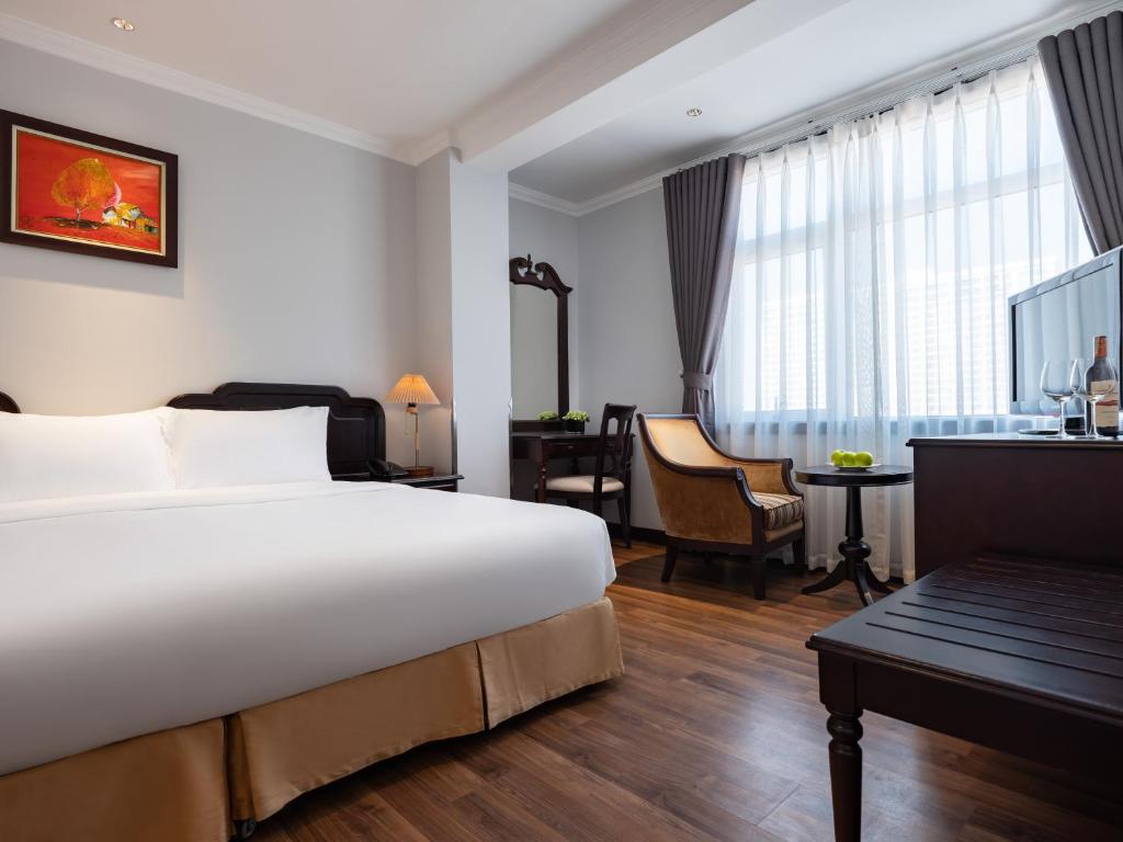 河内Minasi Premium Hotel的酒店客房设有一张大床和一张书桌。