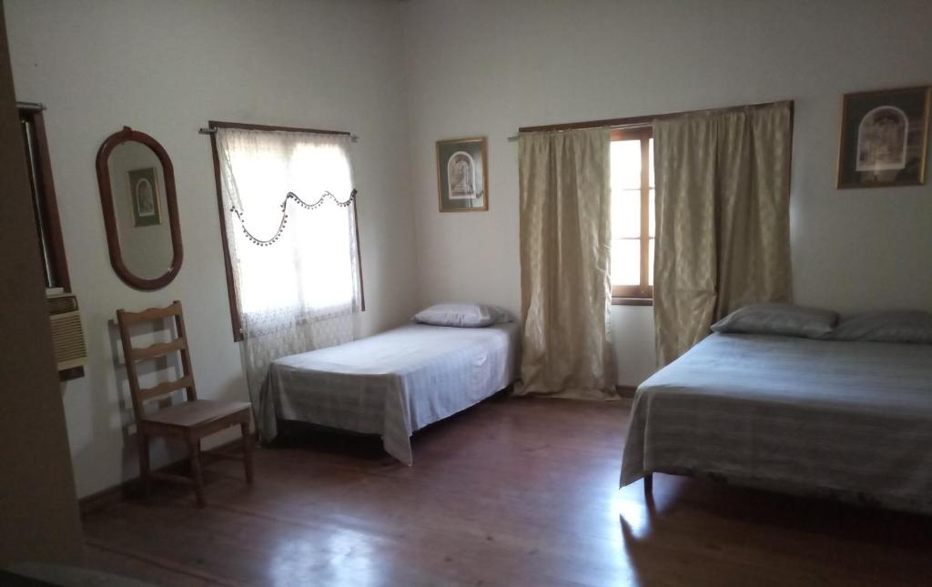 特拉Casa del Campo的一间卧室设有两张床、一把椅子和一个窗户。